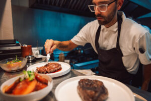 A chef putting the finishing touches to a main course at Criollo Restaurant